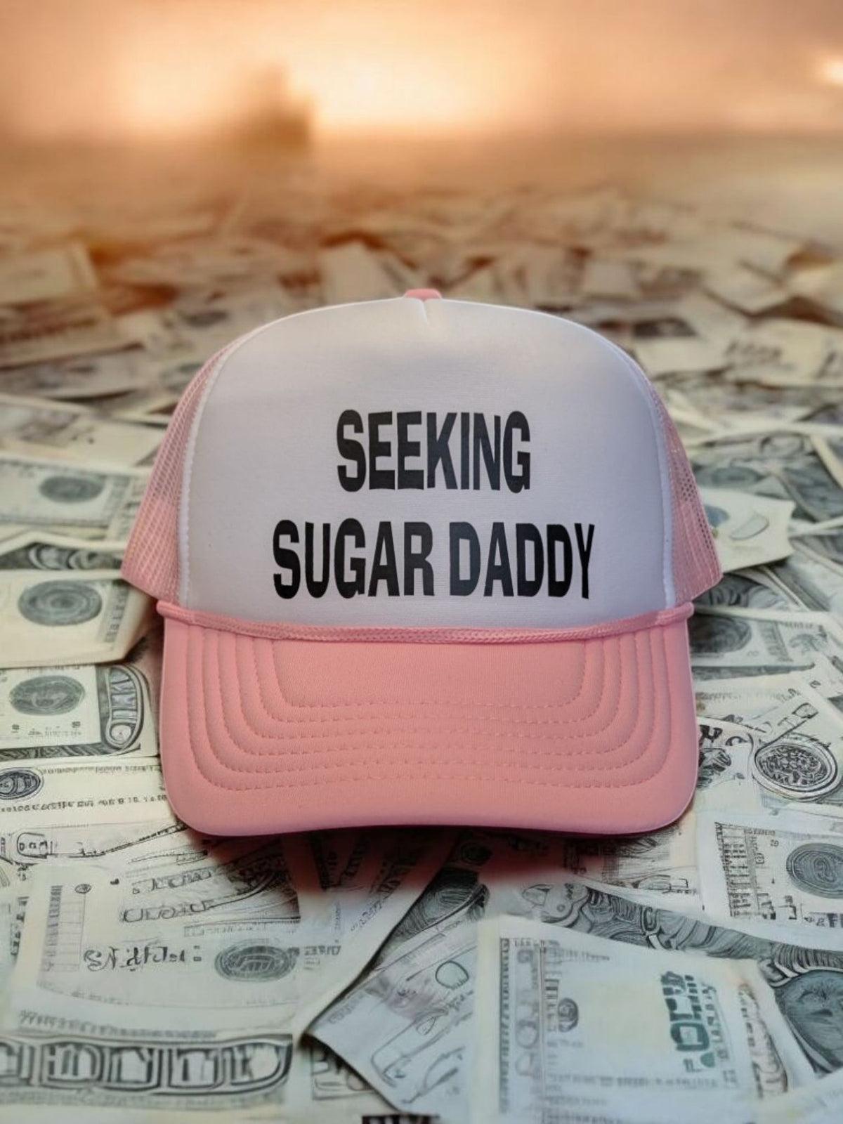 Lakelifewear pink and white foam trucker hat with Seeking Sugar Daddy slogan in black text on a pile of cash